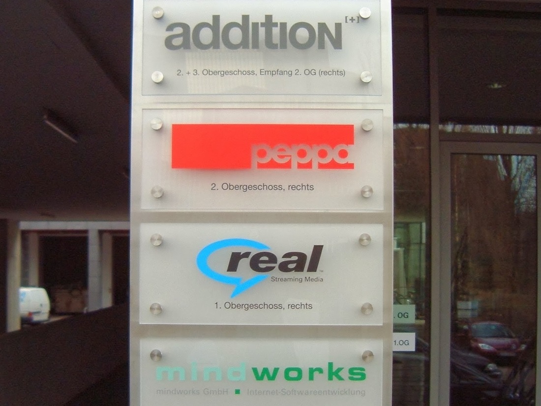 Firmenschilder auf Acrylschilder beschriftet im Hintergrund ist eine Edelstahlplatte die Platten sind mit Edelstahl Abstandshalter befestigt