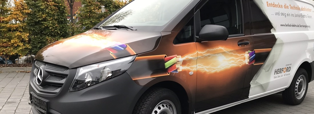 weißes fahrzeug mit digitaldruch beschriftet der hintere teil ist weiß orange schrift auf weiß geklebt