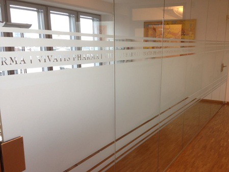 Sichtschutzfolie mit Dekorstreifen und Logo auf Glastrennwand im Büro – elegante Milchglasfolie von Folien Fischer Hamburg Bergedorf. Ideal für Firmen in Reinbek, Glinde, Geesthacht, Lauenburg, Schwarzenbek und Wentorf